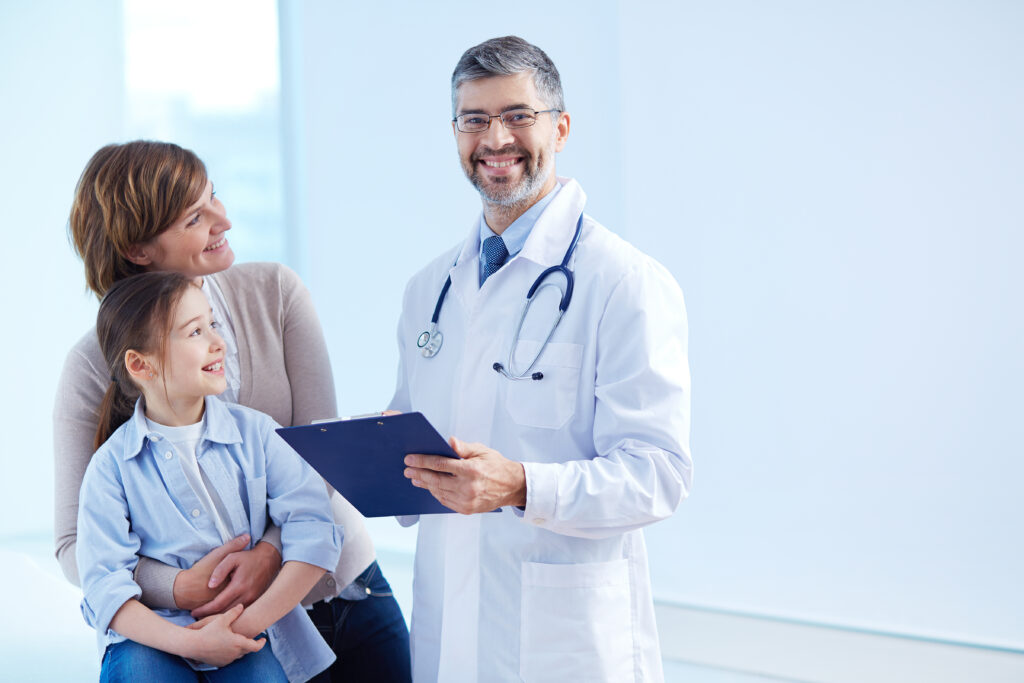 About Us happy doctor holding clipboard with patients 1024x683